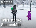 Mutter mit Kind im dichten Schneefall