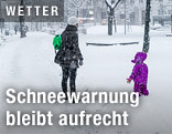 Mutter mit Kind im dichten Schneefall