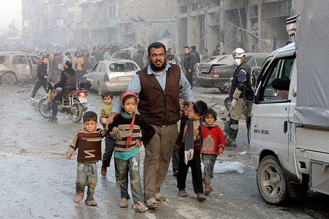 © Reuters/Hosam Katan Ein Mann verlässt mit Kindern den Detonationsort einer Fassbombe in Aleppo