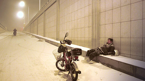 © APA/EPA/Berlinale Filmszene aus "Schwarze Kohle, dünnes Eis" zeigt einen Mann mit Mofa im Schnee am Straßenrand