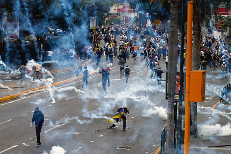 © APA/AP/Fernando Llano Demonstranten flüchten vor Tränengas