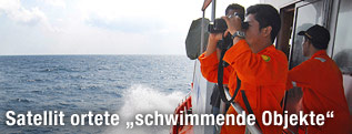 Mann sucht mit Fernglas nach Wrackteilen