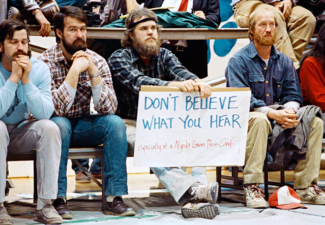 © AP/Rob Stapleton Männer vor einem Plakat mit der Aufschrift "DON'T BELIEVE WHAT YOU HEAR" während einer Pressekonferenz des US-Ölkonzerns ExxonMobil