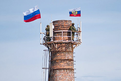Russische Soldaten auf einem Schornstein mit russischen Fahnen
