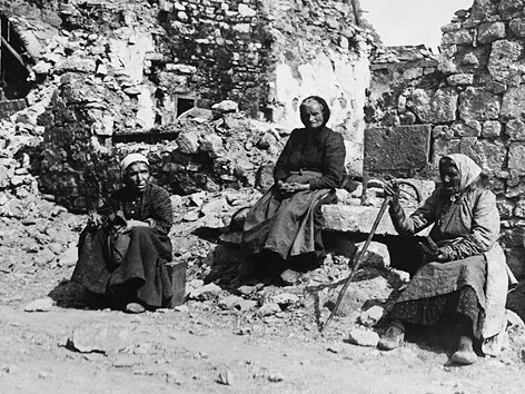 © picturedesk.com/Mary Evans Frauen sitzen vor einem zerstörten Gebäude