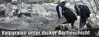 Zwei M&auml;nner r&auml;umen verbrannte Tr&uuml;mmer aus der Asche