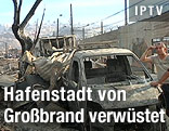 Mann lehnt an einem ausgebrannten Autowrack