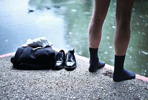 Geschäftsmann steht nur mit Socken bekleidet an einem See
