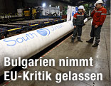 Arbeiter stehen neben einem South-Stream-Rohr