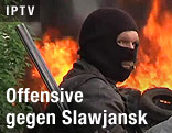 Maskierter Mann vor einem Brand