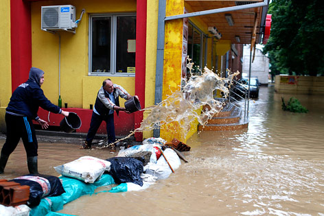 Zwei Männer schütten einen vollen Kübel Wasser aus