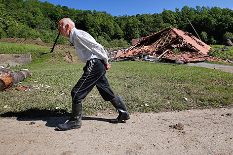 © AP/Amel Emric Ein alter Mann in Gummistiefeln geht an einem zerstörten Haus vorbei