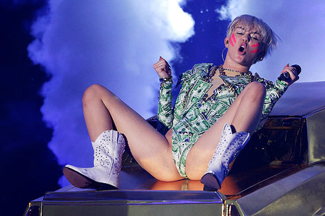 © APA/EPA/Georg Hochmuth Miley Cyrus liegt auf dem Dach eines Autos