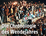 Das Archivbild vom 11.11.1989 zeigt jubelnde Menschen, die mit Wunderkerzen auf der Berliner Mauer sitzen.