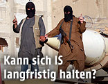 Vermummte IS-Kämpfer posieren neben einer Rakete