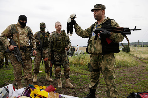 © APA/AP/Dmitry Lovetsky Pro-russische Rebellen stehen an der Absturzstelle, einer von ihnen hält ein Plüschtier hoch
