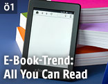 E-Book-Reader lehnt an Bücherstapel