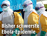 Männer in Schutzanzügen beim Abtransport einer Ebola-Toten