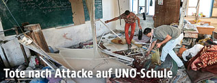 Zwei Männner zwischen Trümmern in einem Klassenzimmer