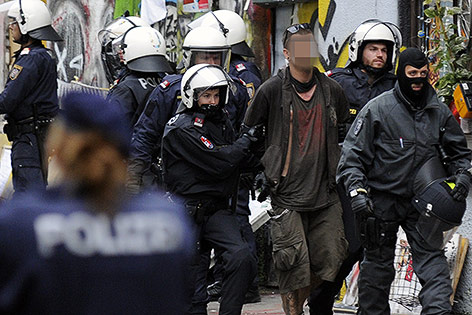 Polizisten führen einen Hausbesetzer ab