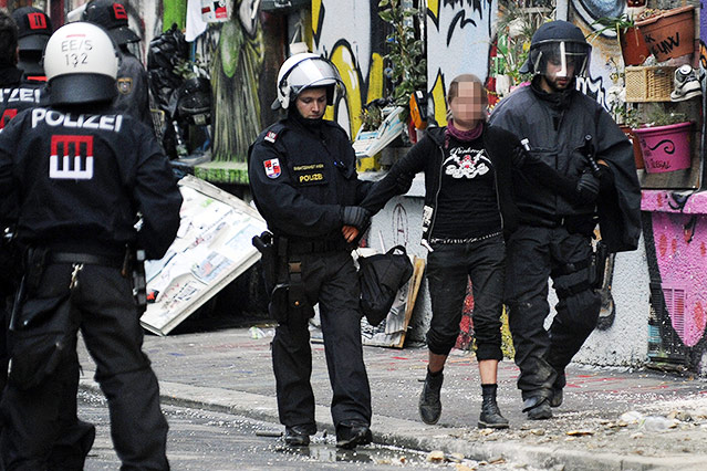 Polizisten führen eine Hausbesetzerin ab