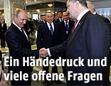Wladimir Putin und Petro Poroschenko schütteln die Hände
