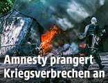Mann geht an brennenden Trümmern vorbei