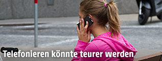 Frau telefoniert  auf Parkbank sitzend
