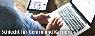 Person arbeitet gleichzeit mit Laptop und Tablet