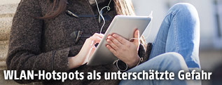 Frau sitzt an einem &ouml;ffentlichen Platz mit ihrem Tablet-PC