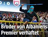 Ein vermummter Mann mit Stange &uuml;berspringt eine Stadionabsperrung