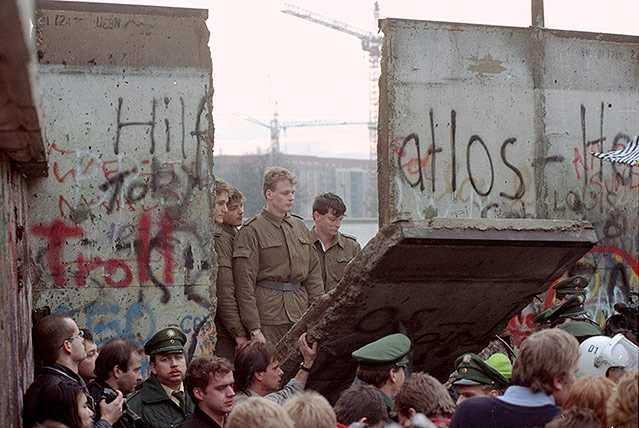 © AP/Lionel Cironneau Polizisten schauen durch ein Loch in der Berliner Mauer