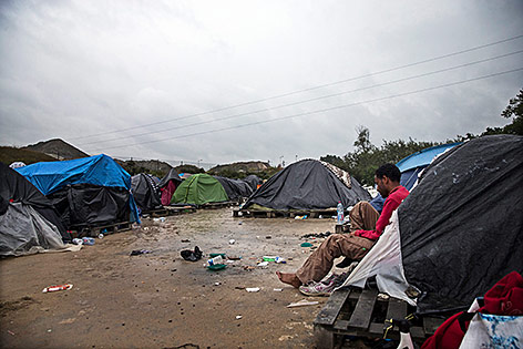 © APA/EPA/Etienne Laurent Ein afrikanischer Flüchtling sitzt neben Zelten