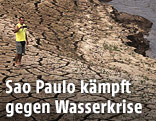Mann steht in ausgetrocknetem Flussbett