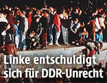 Das Archivbild vom 09.11.1989 zeigt jubelnde Menschen auf der Berliner Mauer vor dem Brandenburger Tor