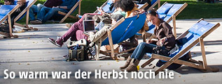 Junge Menschen sitzen in Liegest&uuml;hlen in der Sonne