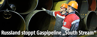 Arbeiter stehen neben Gaspipelinerohren
