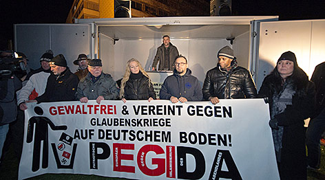 Demonstranten halten ein Pediga-Banner