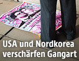 Plakat des Films "The Interview" auf dem Boden neben den Beinen eines Mannes