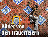 Mann klettert eine Wand zu einer Namensplakette hoch