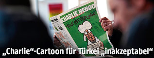 Mann h&auml;lt Ausgabe der Zeitung "Charlie Hebdo"