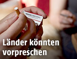 Eine Person nimmt eine Zigarette aus der Packung