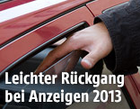 Hand greift in ein offenes Autofenster
