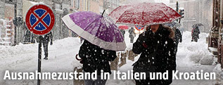 Personen mit Regenschirmen im Schneegestöber