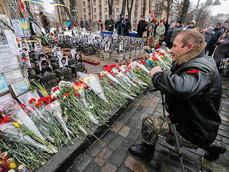 © APA/EPA/Sergey Dolzhenko Trauernder Mann vor Blumen auf dem Maidan