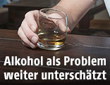 Mann h&auml;lt ein Glas auf eine Tisch