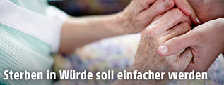 Pflegerin h&auml;lt H&auml;nde einer Patientin
