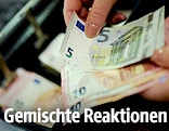 Geldscheine werden in eine Registrierkasse gelegt