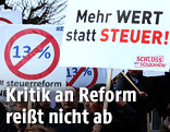 Demonstranten mit Protestschildern gegen die geplante Steuerreform
