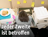 Hinteransicht einer gestressten Frau am Arbeitsplatz